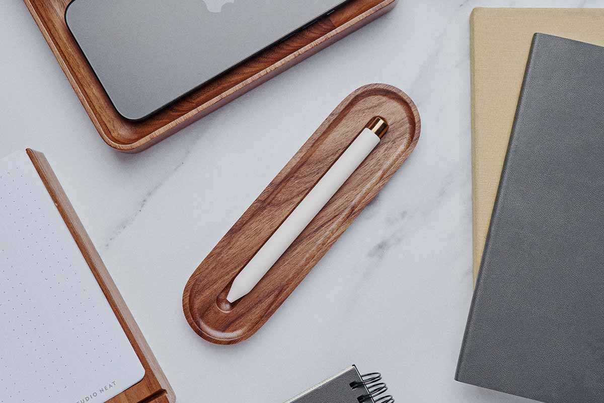 A pen tray on a desk with notebooks.