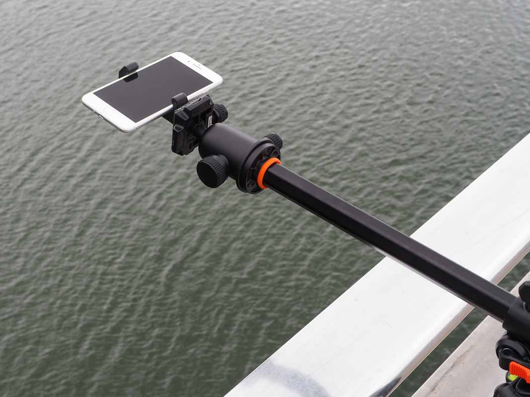 the glif holding a phone over water via a tripod arm.