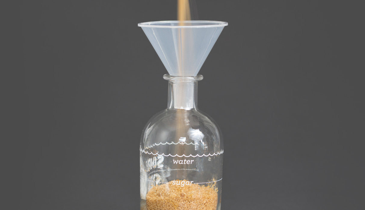 sugar being poured into the bottle via a funnel.