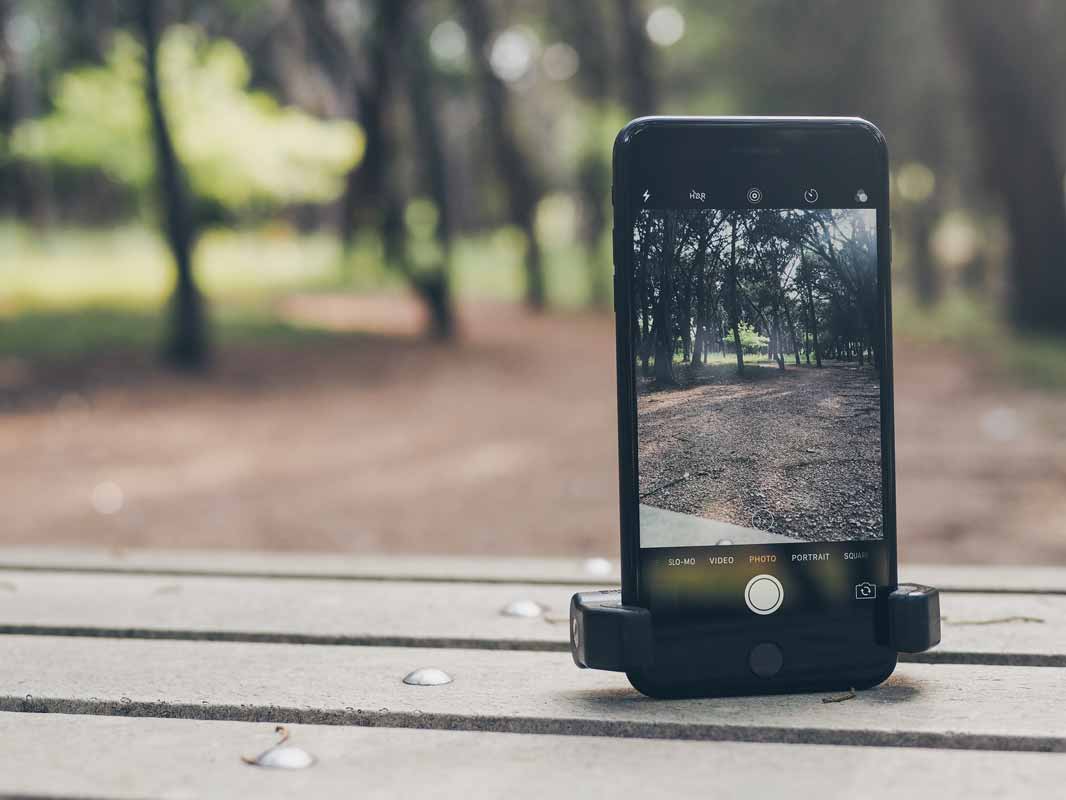 the glif holding a phone upright with no tripod on a park bench.