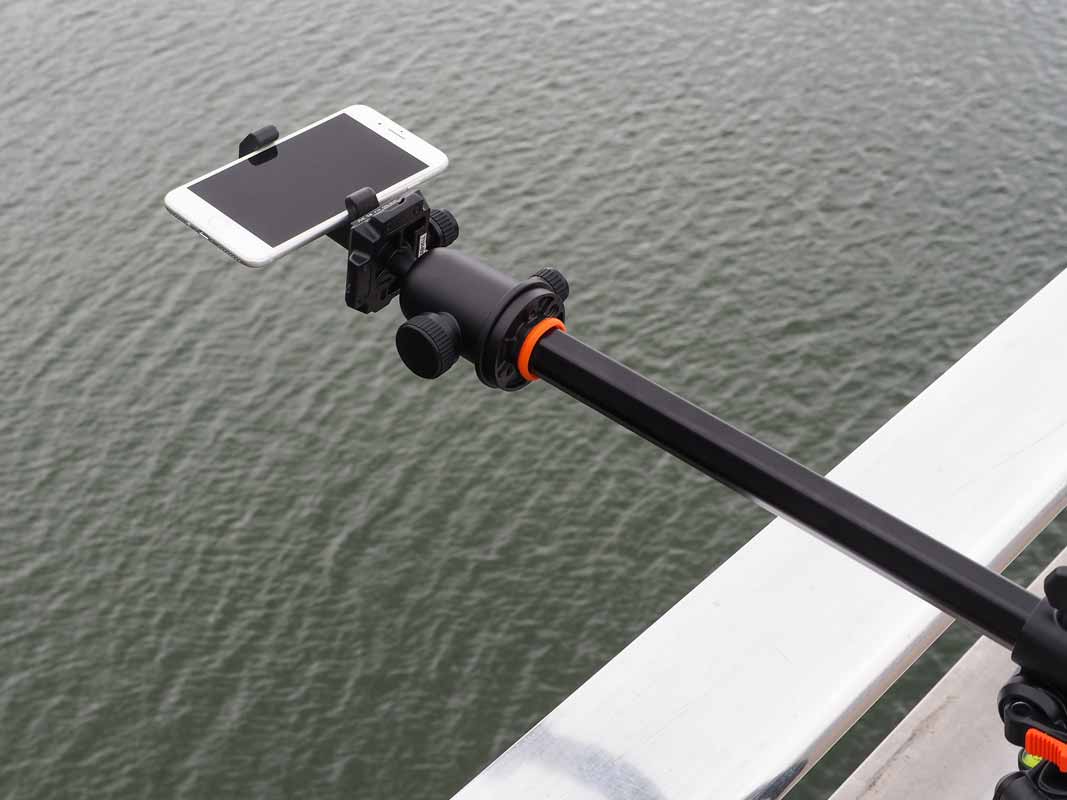 the glif holding a phone over water via a tripod arm.